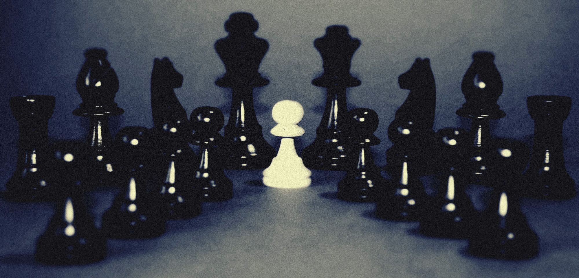 A single white pawn surrounded by black chess pieces