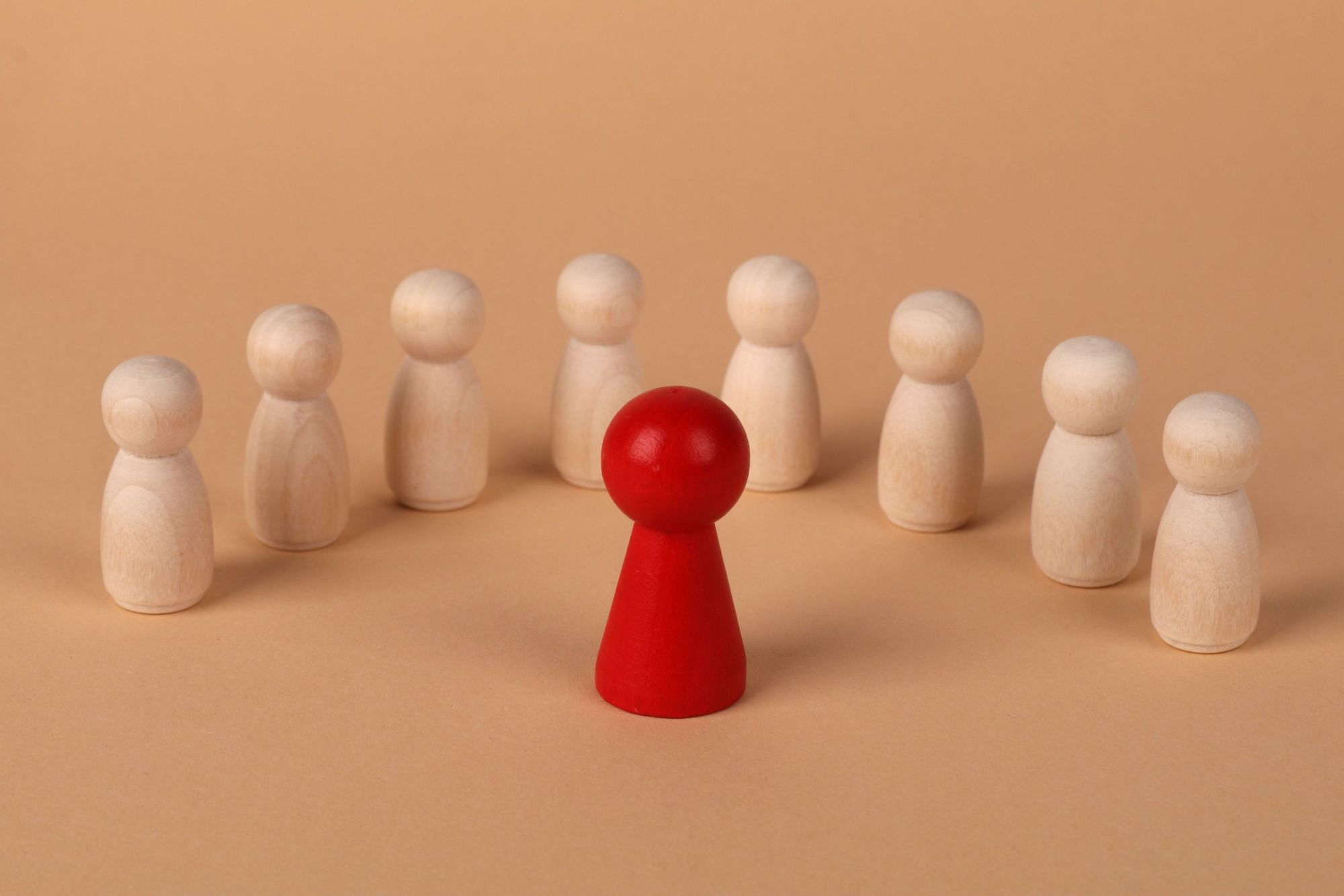 A red figure standing in front of a circle of wooden figures
